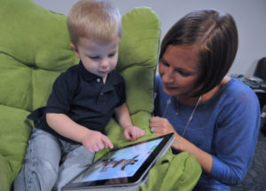 A child reading on his iPad with his mother