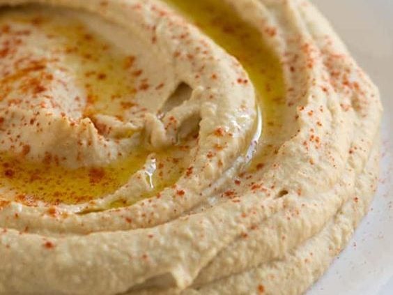 Hummus with red spice and olive oil on top and served on a white plate. for this food entry. caribu mommy mom mother's blog that gives parenting advice for kids, children, toddlers, preschoolers.